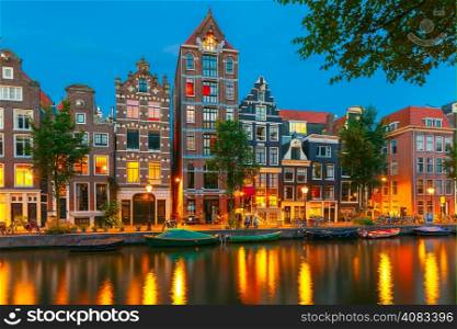 Night city view of Amsterdam canal Herengracht, typical dutch houses and boats, Holland, Netherlands.