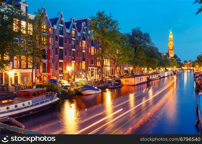Night city view of Amsterdam canal Prinsengracht with houseboats and Westerkerk church and luminous track from the boat, Holland, Netherlands. Used toning