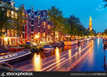 Night city view of Amsterdam canal Prinsengracht with houseboats and Westerkerk church and luminous track from the boat, Holland, Netherlands. Used toning