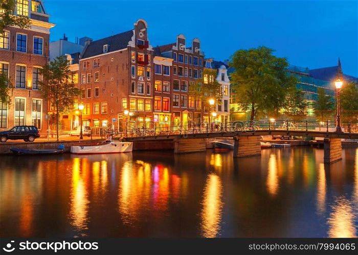 Night city view of Amsterdam canal, typical dutch houses and bridge, Holland, Netherlands.