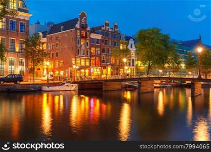Night city view of Amsterdam canal, typical dutch houses and bridge, Holland, Netherlands.