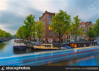 Night city view of Amsterdam canal with bridges and luminous track from the boat, Holland, Netherlands.