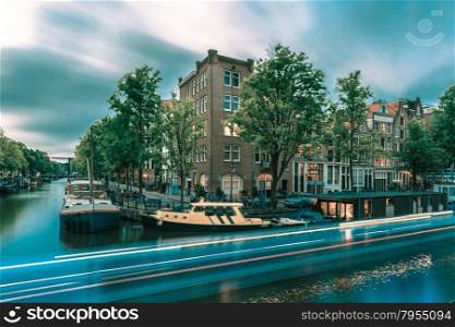 Night city view of Amsterdam canal with bridges and luminous track from the boat, Holland, Netherlands.. Toning in cool tones