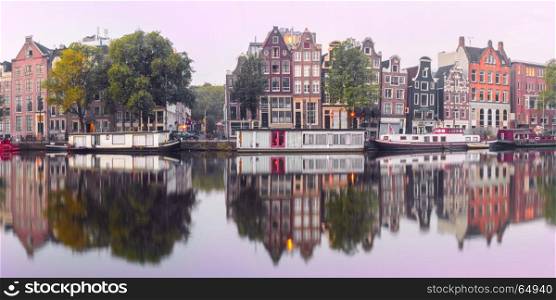 Night city view of Amsterdam canal with dutch houses. Panorama of Amsterdam canal Amstel with typical dutch houses and houseboat from the boat in the morning, Holland, Netherlands.