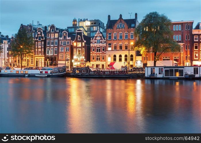 Night city view of Amsterdam canal with dutch houses. Amsterdam canal Amstel with typical dutch houses and houseboat from the boat in the morning, Holland, Netherlands.