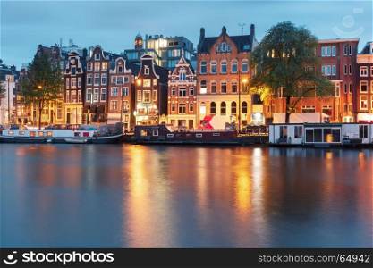 Night city view of Amsterdam canal with dutch houses. Amsterdam canal Amstel with typical dutch houses and houseboat from the boat in the morning, Holland, Netherlands.