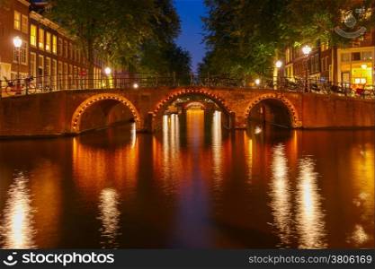 Night city view of Amsterdam canals and seven bridges, Holland, Netherlands.