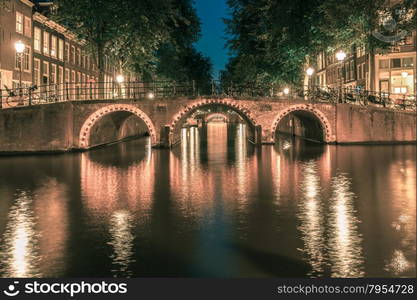 Night city view of Amsterdam canals and seven bridges, Holland, Netherlands.. Toning in cool tones