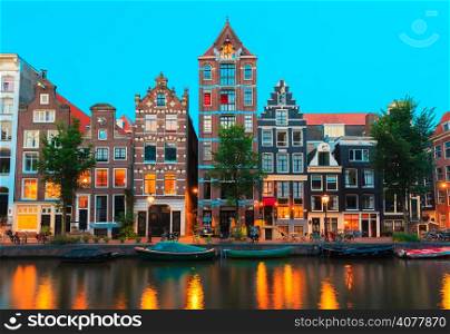 Night city view of Amsterdam canals and typical houses, boats and bicycles, Holland, Netherlands.