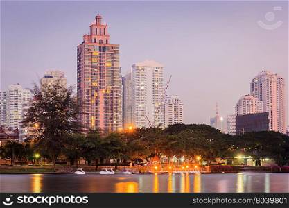 Night cityscape, office buildings and apartments in Thailand at dusk. View from public park.