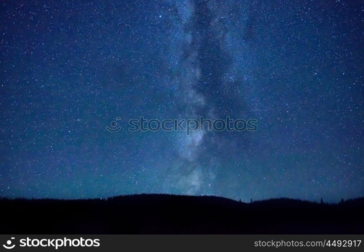 Night dark blue sky with many stars and milky way galaxy above a mountain