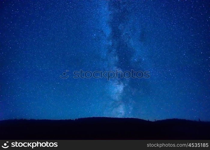 Night dark blue sky with many stars and milky way galaxy above a mountain