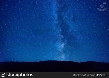 Night dark blue sky with many stars and milky way galaxy above a mountain