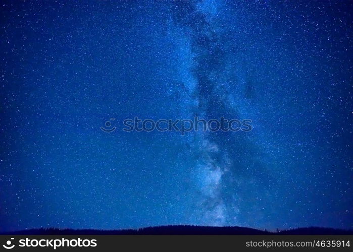 Night dark blue sky with many stars and milky way galaxy above a mountain