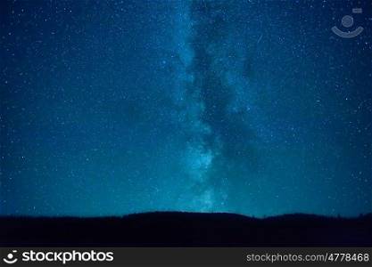 Night dark blue sky with many stars and milky way galaxy above a mountain