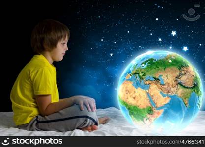 Night dreaming. Cute boy sitting in bed and dreaming. Elements of this image are furnished by NASA