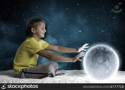 Night dreaming. Cute boy sitting in bed and dreaming about moon