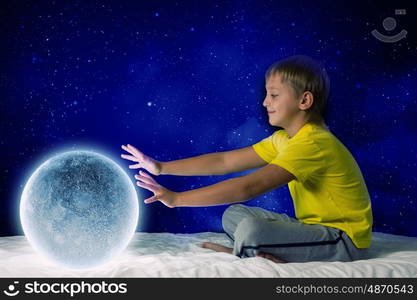 Night dreaming. Cute boy sitting in bed and dreaming about moon