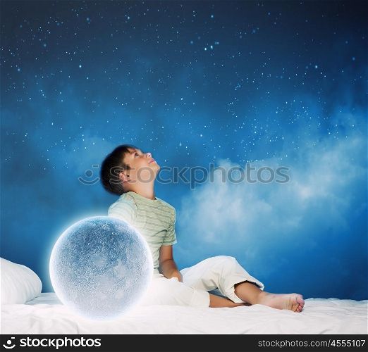 Night dreaming. Cute boy sitting in bed with moon