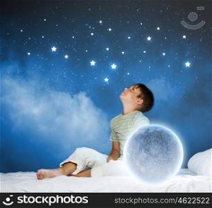 Night dreaming. Cute boy sitting in bed with moon
