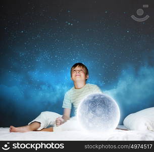 Night dreaming. Cute boy sitting in bed with moon