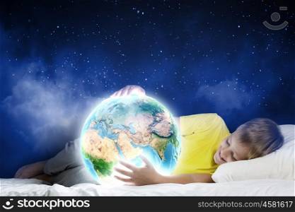 Night dreaming. Cute boy sleeping in bed holding Earth planet. Elements of this image are furnished by NASA