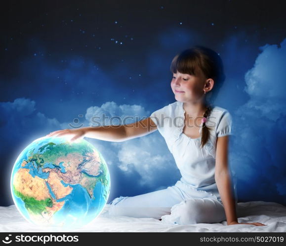 Night dreaming. Cute girl sitting in bed and looking at Earth planet. Elements of this image are furnished by NASA