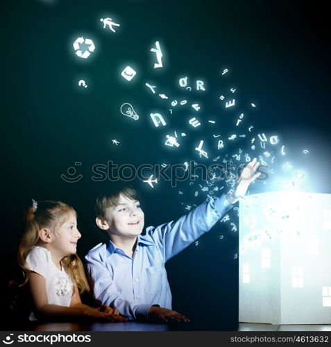 Night dreaming. Cute little boy and girl looking at model of house