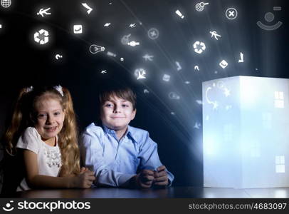 Night dreaming. Cute little boy and girl looking at model of house