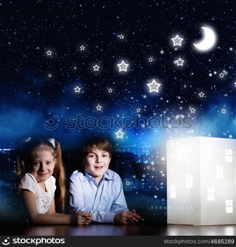 Night dreaming. Cute little boy and girl looking at model of house