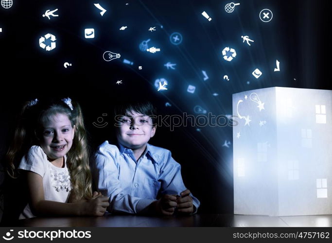 Night dreaming. Cute little boy and girl looking at model of house