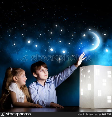 Night dreaming. Cute little boy and girl looking at model of house