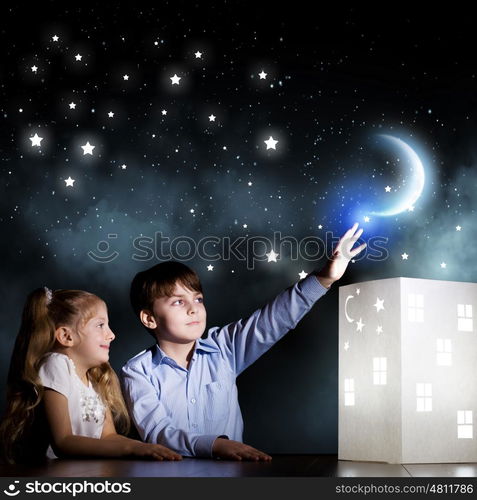 Night dreaming. Cute little boy and girl looking at model of house