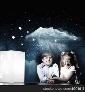 Night dreaming. Cute little boy and girl looking at model of house