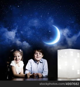 Night dreaming. Cute little boy and girl looking at model of house