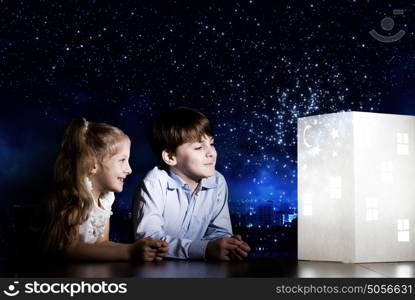 Night dreaming. Cute little boy and girl looking at model of house