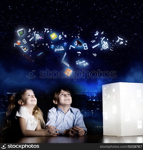 Night dreaming. Cute little boy and girl looking at model of house