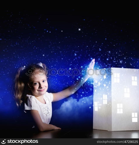 Night dreaming. Cute little girl looking at model of house and dreaming