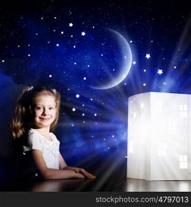 Night dreaming. Cute little girl looking at model of house and dreaming