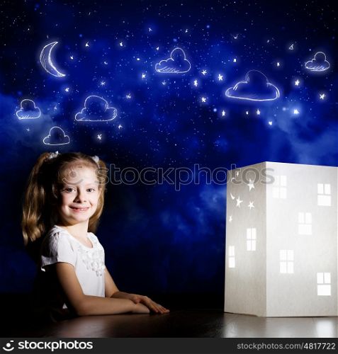 Night dreaming. Cute little girl looking at model of house and dreaming