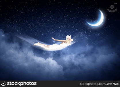 Night dreaming. Young blond girl flying in night sky