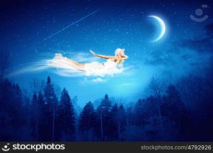 Night dreaming. Young blond girl flying in night sky
