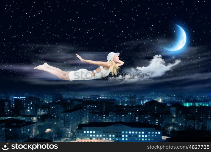 Night dreaming. Young blond girl flying in night sky