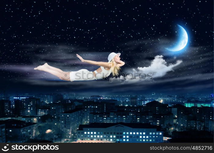 Night dreaming. Young blond girl flying in night sky