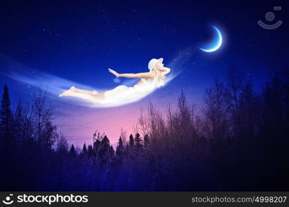 Night dreaming. Young blond girl flying in night sky