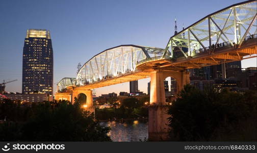 Night falls as pedestrians walk across a bridge for an event