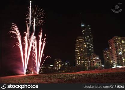 Night firework display exploding with Surfers Paradise city skyline in Australia.