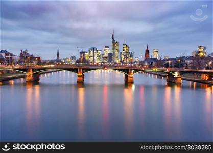 Night Frankfurt am Main, Germany. Picturesque view of Frankfurt am Main skyline and Ignatz Bubis Brucke bridge during evening blue hour with mirror reflections in the river, Germany