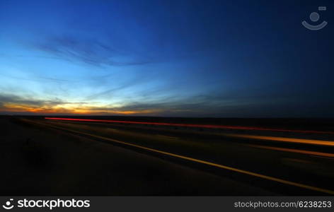 Night highway with dramatic sky &amp; car lights in motion