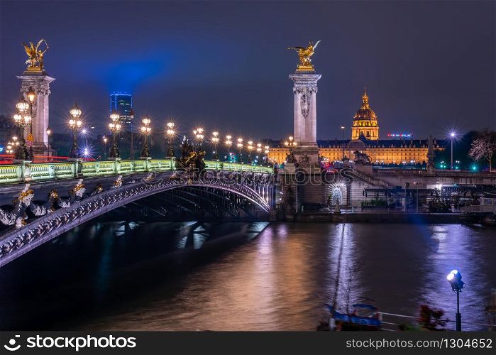 Night illuminated view of The Pont Alexandre the third above the Seine river and The Petit Palais, small palace art museum in Paris. Bright night cityscape and illumination.